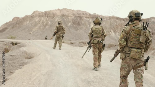Soldiers in camouflage uniforms aiming with their rifles ready to fire during military operation in the desert