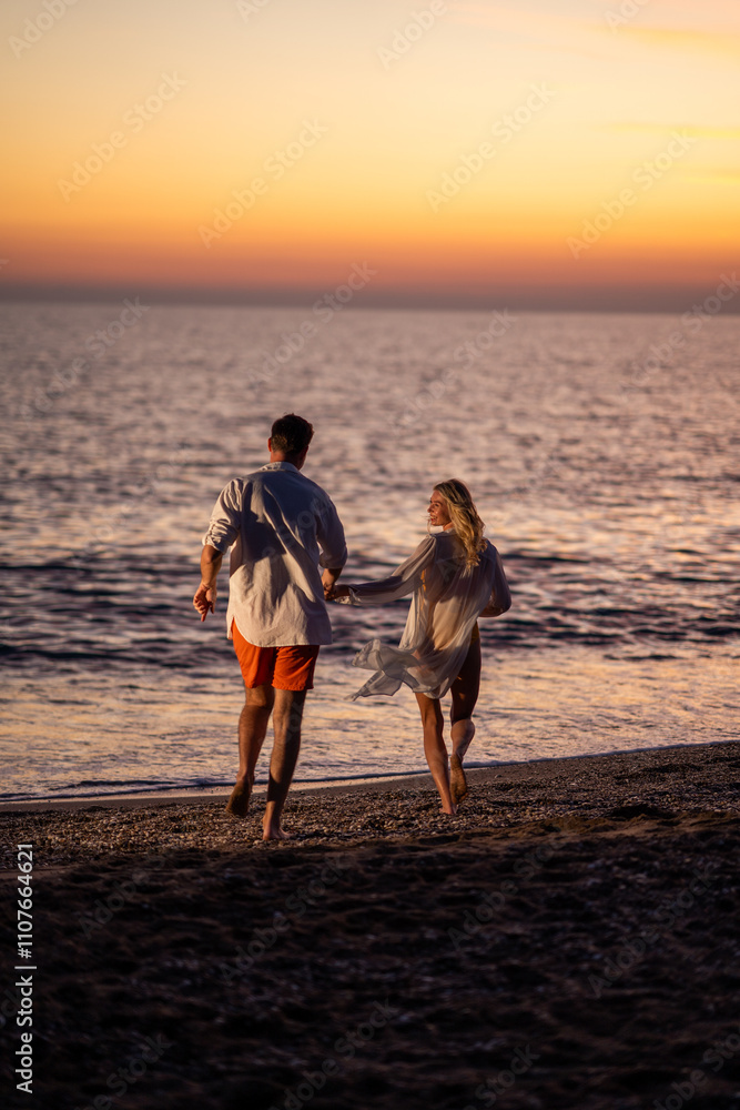 Fototapeta premium A happy couple sharing romantic moments at the beach during sunset, with the golden hues of the setting sun creating a serene and intimate atmosphere.