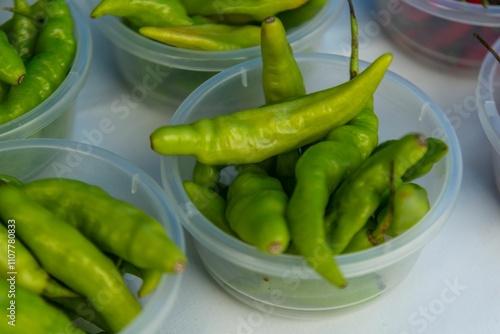 Fresh green chili peppers in containers photo