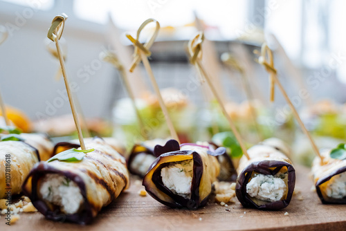 A beautifully crafted wooden cutting board is arranged with an appealing display of various rolls of delicious food presented elegantly on toothpicks. Perfect for sharing