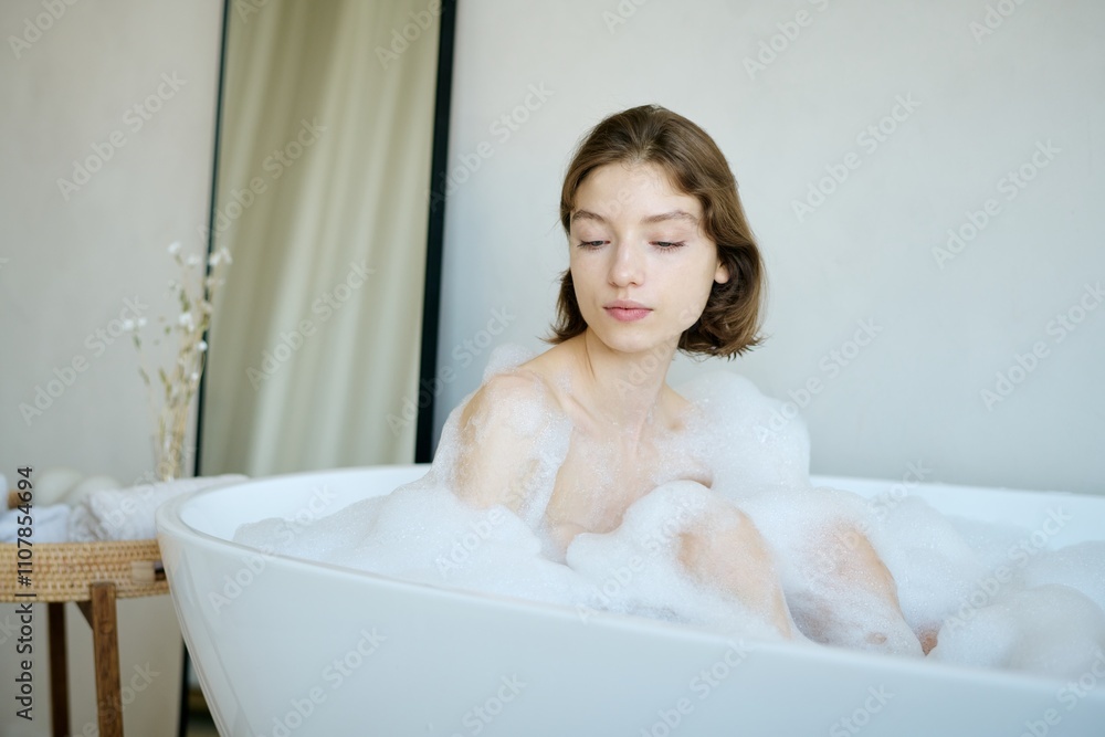 Obraz premium Charming Caucasian woman enjoying time in hot bathtub with foam after work week