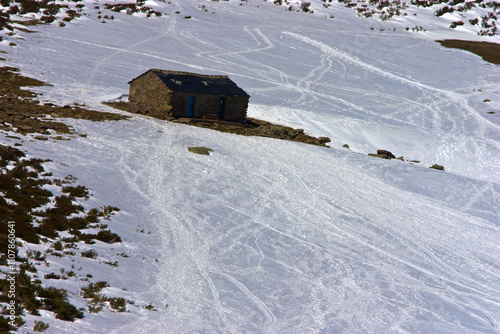 Uma pequena cabana no meio da neve. Uma encosta coberta de neve onde se marca de sky. photo