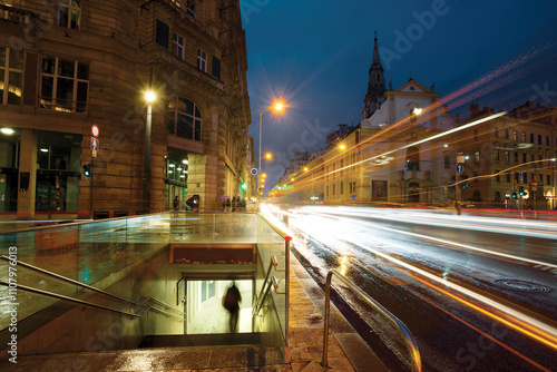 Traffic motion lights, figure descending into an underground passage in the city
