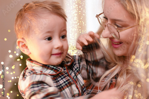 Portrait of a young woman in glasses and a small one and a half year old child. Mother looks lovingly at the baby, smiling photo