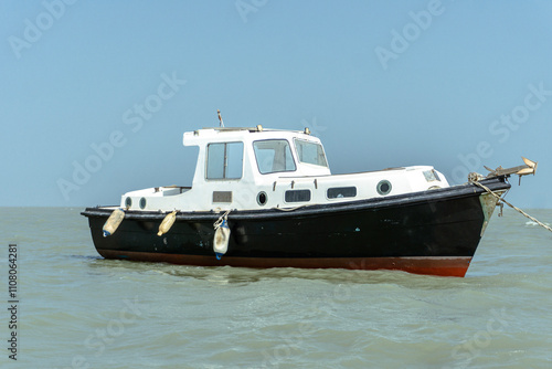 Vintage Motorboat Anchored in calm waters under bright blue sky view, Rustic Marine Vessel Against a Clear Sky,  photo