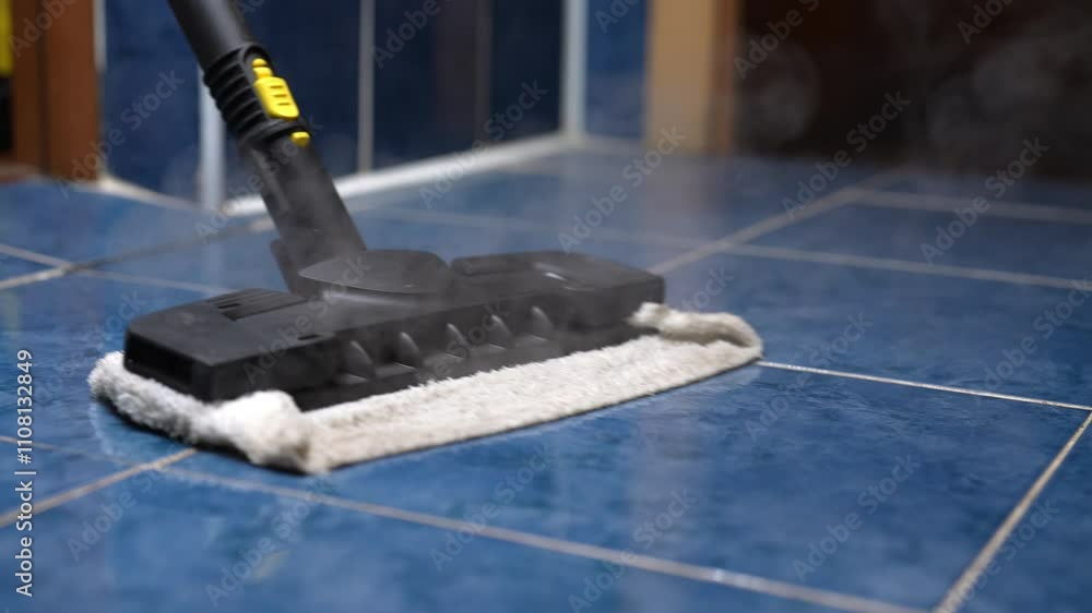 Closeup of cleaning company worker keeping home healthy with germ-free blue bathroom tile floor using steam mop for steam cleaning. Concept of cleaning and household. Shooting in slow motion.