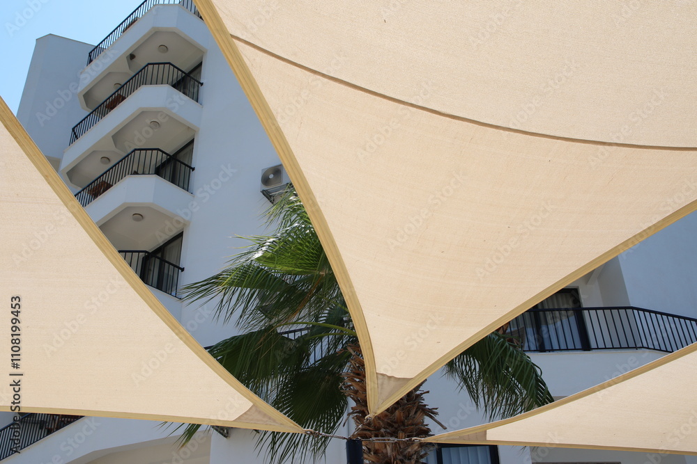 Modern architectural design with a beige shade sail providing shade over a building, perfect for a contemporary architecture or design project