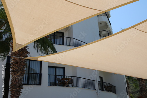 Minimalist exterior design with a clean white building and a beige shade sail, perfect for a home decor or architecture magazine