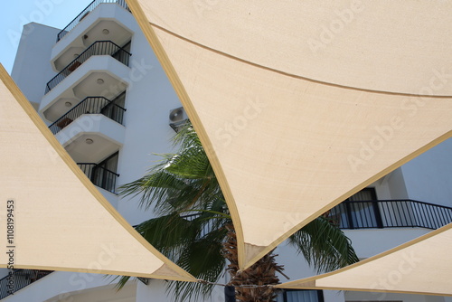 Obraz na płótnie Modern architectural design with a beige shade sail providing shade over a building, perfect for a contemporary architecture or design project w salonie