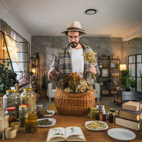 Bilde på lerret Adult man herbalist arranging herbs in basket at workshop