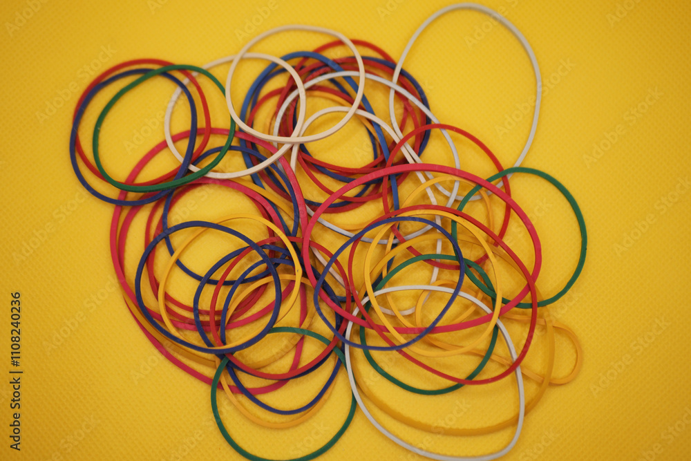 Colorful rubber bands are displayed on a bright yellow background Colorful rubber bands are displayed on a bright yellow background