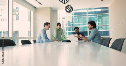 Diverse businesspeople engage in consultancy discussions sitting at negotiation table. Indian president leads conversation, emphasizing communication and teamwork during advisory session photo