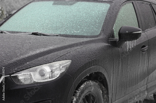 The car was iced over in winter after an icy rain. The windshield was covered with ice. Frost, rain and a car. Blurred background