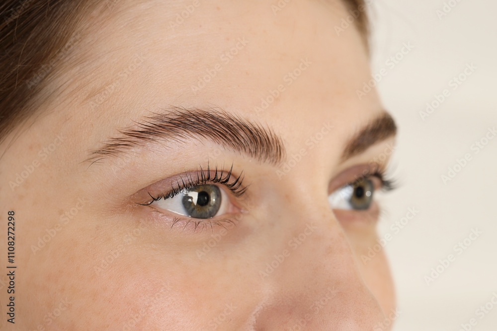 Naklejka premium Beautiful woman after lash laminating and tinting procedure on light background, closeup