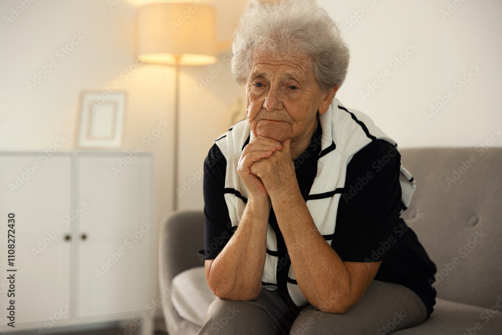 Loneliness concept. Sad senior woman sitting on sofa at home Loneliness concept. Sad senior woman sitting on sofa at home