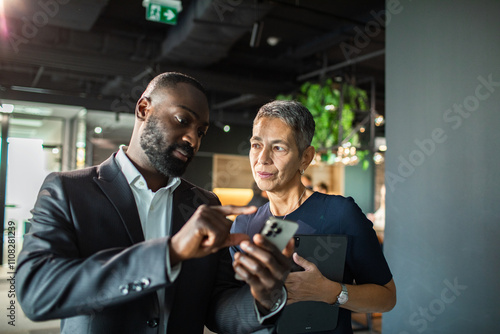 Business colleagues discussing project using smartphone in modern office photo