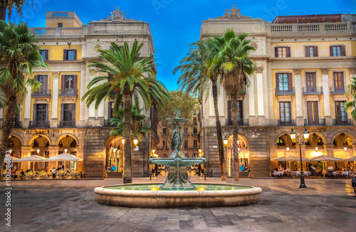 Photography Diners enjoy the peaceful setting, flowing fountain and palm trees of the Plaça Reial (Royal Square) at blue hour on a summer evening in Barcelona, Spain