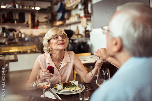 Senior couple celebrating anniversary at restaurant with gifts photo