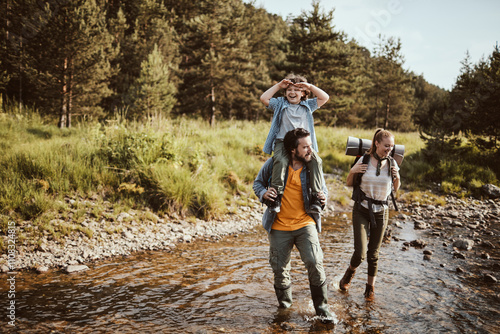 Young family crossing a creek and hiking in the forest photo