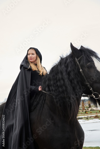 Принти на полотні woman princess in black cloak sits astride black steed horse