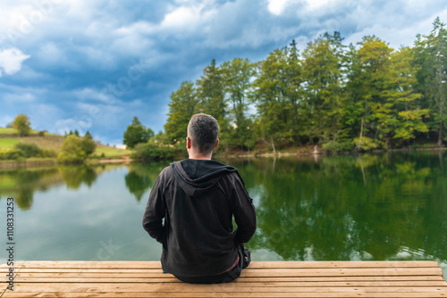 A man sitting on the porch and watching the lake.