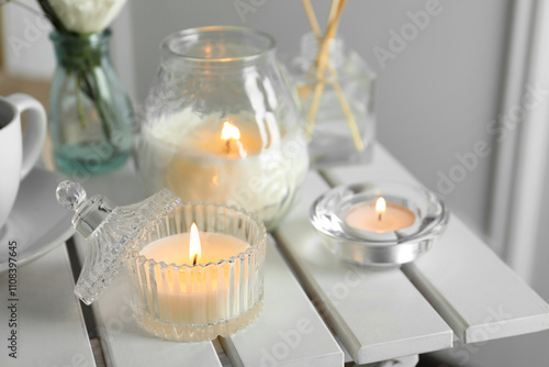 Tableau sur toile Beautiful burning candle on white wooden table, closeup