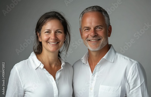 The man and woman casual attire business shirt and warm smiles highlight a simple yet strong business partnership standing together on white background. photo