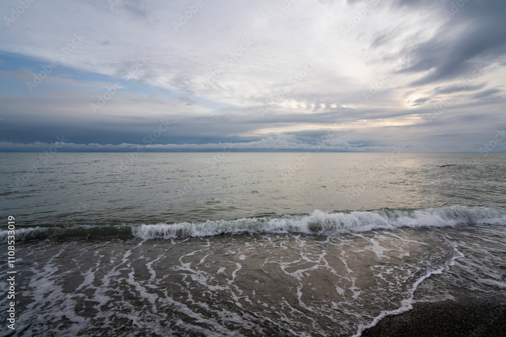 Fototapeta premium An incoming wave on the Black Sea coast against the sunset sky, Sochi, Krasnodar Territory, Russia
