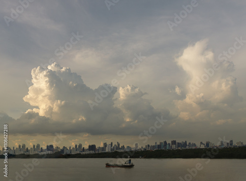 Beautiful Clouds in the Sky over Large Metropolitan City of Bangkok along Chao praya riverside with cargo ship. View of Skyscrapers and Dramatic Sky before Sunset, Space for text, Selective focus. photo