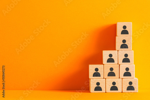 Stacked wooden blocks with black human icons on a vibrant orange background, illustrating teamwork, organization, and growth concepts.