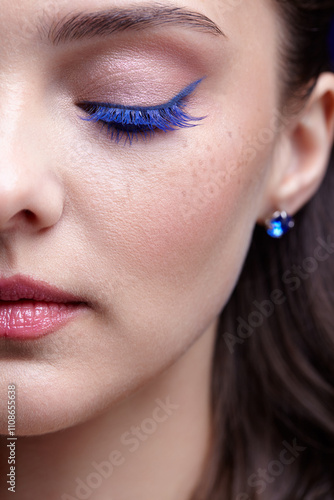 Portrait of young female face. Woman with blue beauty eyes makeup wears earrings with rhinestone. Eye closed. photo