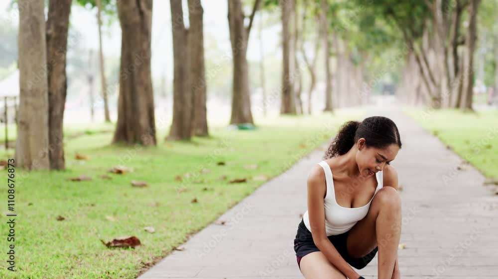 Young sporty woman tying shoelaces on a park pathway getting ready for jogging in the morning Young sporty woman tying shoelaces on a park pathway getting ready for jogging in the morning