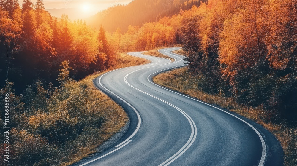 Naklejka premium Winding asphalt road through autumn forest, sunlit. Perfect for travel, adventure, and fall season themes; evokes journey and freedom.