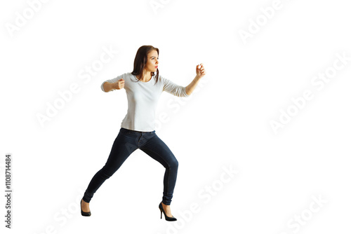Woman in a martial arts defensive stance, wearing casual clothes and high heels, isolated on a white background. Concept of self-defense and empowerment