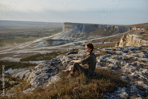 Woman admiring breathtaking view of valley and mountains from cliff edge in travel adventure concept photo