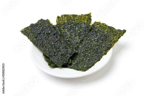 Crispy fried seaweed place on white dish isolated on white background. Algae are plants that grow in lakes, rivers, and other bodies of water. Seaweed has many benefits and is a snack for weight loss.