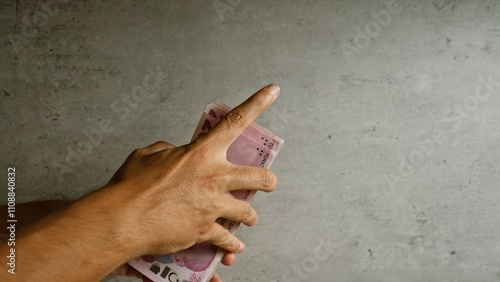 Man holding a stack of turkish lira in his hands against a concrete background, focusing on the act of counting money and financial themes. photo