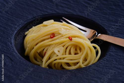 Spaghetti Colatura di Alici with Garlic and Peperoncini on a Black Plate Close Up photo