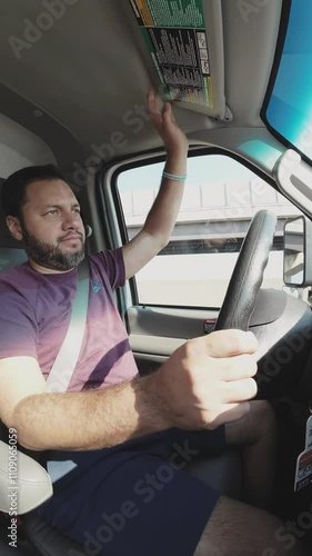 Truck driver adjusts the sun visor while navigating the highway, ensuring comfort and safety during the journey
