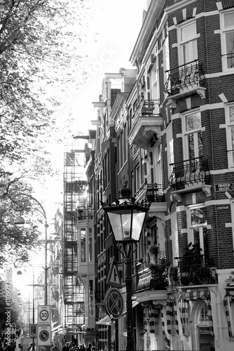 Alte Straßenlaterne an der Prinsengracht mit alten Fassaden in der Altstadt von Amsterdam, der Hauptstadt der Niederlande, fotografiert in neorealistischem Schwarzweiß