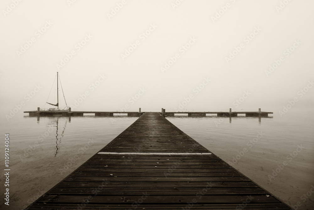 Fototapeta premium LANDSCAPE BY THE LAKE - A sailboat at the pier on a misty morning