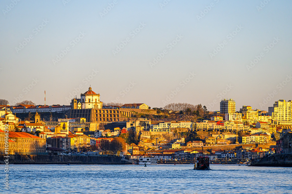 Obraz premium Cityscape by the waterfront district, featuring a vessel moving in the Douro River