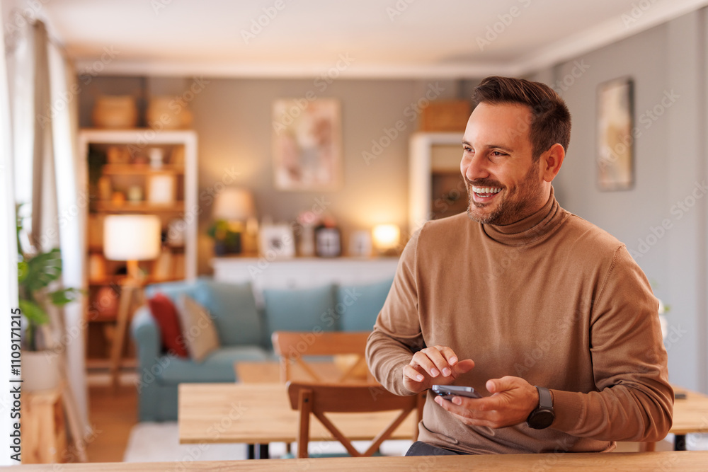 Portrait of cheerful mid adult man messaging online over mobile phone while sitting in home office Portrait of cheerful mid adult man messaging online over mobile phone while sitting in home office