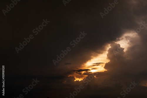 A dark sky with a bright sun peeking through the clouds