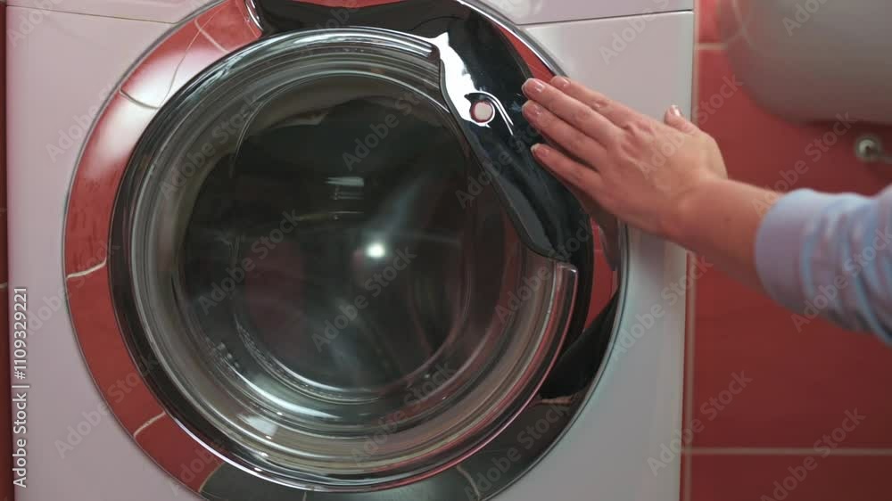 Hand closing washing machine door close-up of hand closing door of front-loading washing machine sleek design and modern interior emphasize household appliances and chores. washing machine Hand closing washing machine door close-up of hand closing door of front-loading washing machine sleek design and modern interior emphasize household appliances and chores. washing machine