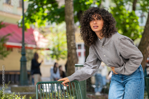 Young woman traveler feeling sudden strong abdominal stomach ache gastritis problem. Upset tourist lady having symptom poisoning diarrhea indigestion peptic ulcer pancreatitis on sunny city street photo