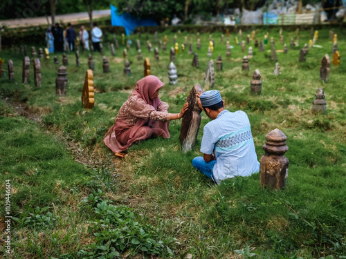 Indonesia - Baubau, 10 May 2024 - Two men and a woman are visiting graves photo