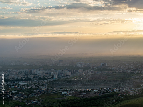 Drone view of clouds at sunset. Beautiful clouds in the sky, haze covered the town. Summer evening landscape.