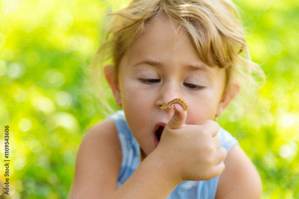 Child looking at caterpillar in garden. Selective focus. Child looking at caterpillar in garden. Selective focus.