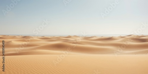 A vast expanse of sand dunes stretches towards the horizon, revealing a sliver of blue sky and a distant glimmer of water.